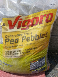 Pea gravel runs a little over $4 a bag. If you are considering having a truck deliver a load from a local rock yard: you will also need to consider the delivery fee. You will need an enormous amount of rock to be successful.